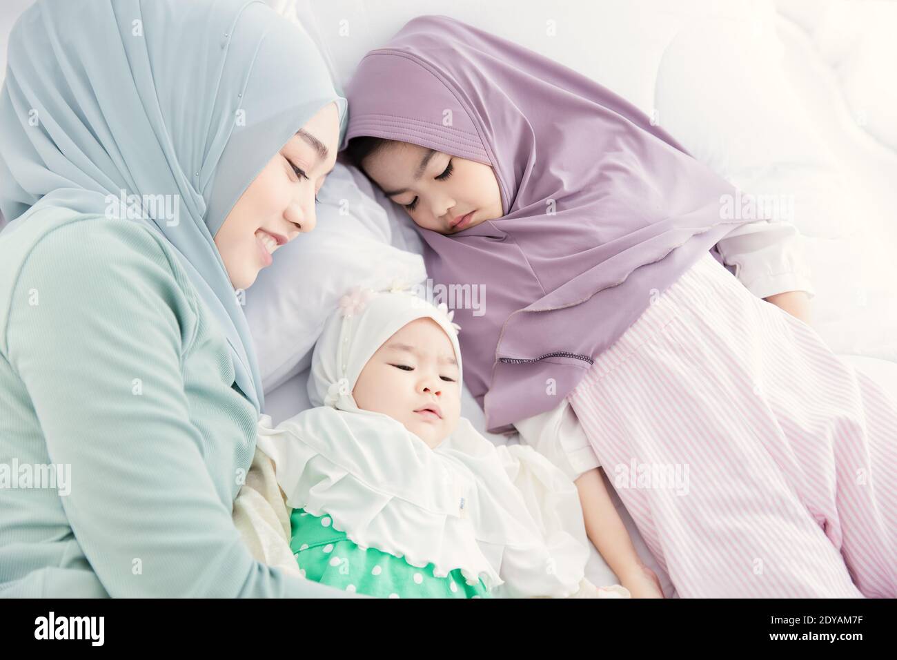 Muslim Hijab Mutter suchen und kuscheln schlafen Baby mit Liebe und Sorgfalt auf dem Bett. Stockfoto