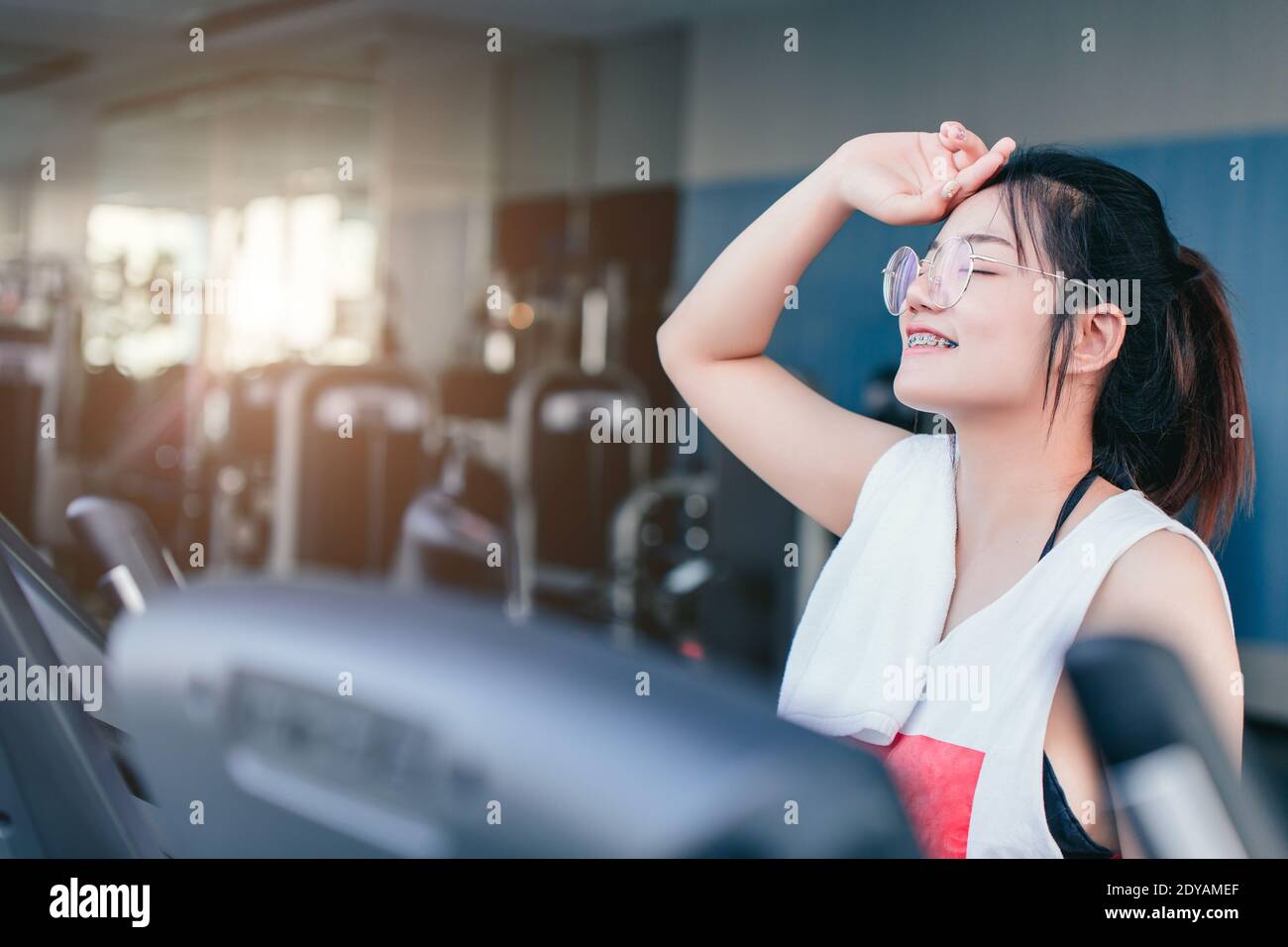 Asiatische Teenager Zahnspange Mädchen Cardio-Training Übung im Sportverein Mit einem Handtuch auf den Schultern lächelnd nach dem Training auf dem Laufband In der Turnhalle suchen Camcorder Stockfoto