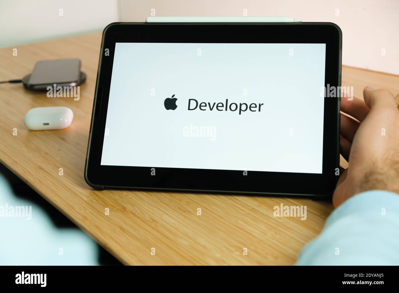 Apple Entwickler-Logo auf dem Bildschirm des iPad Tablet mit Smartphone iPhone wird über das kabellose Ladegerät und die airpods aufgeladen Im Fall auf dem Hintergrund Stockfoto