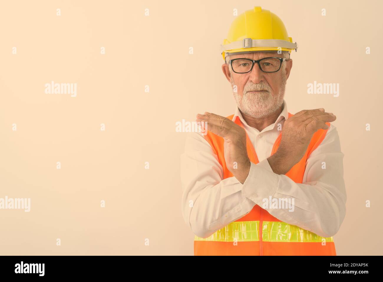 Studioaufnahme eines gutaussehenden älteren bärtigen Bauarbeiters Halten Sie die Handbewegung mit beiden Händen an, während Sie eine Brille tragen Weiß Stockfoto