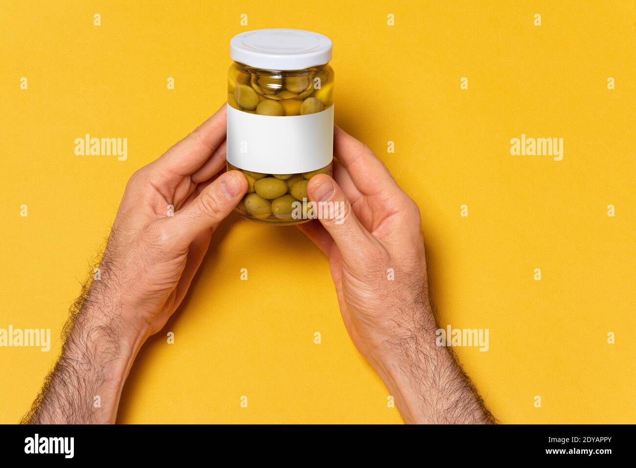 Grüne Oliven konservieren glasig Glas mit runden Kappe auf den Händen, editierbare Modell-up-Serie Vorlage bereit für Ihr Design, Label-Auswahl-Pfad enthalten. Stockfoto