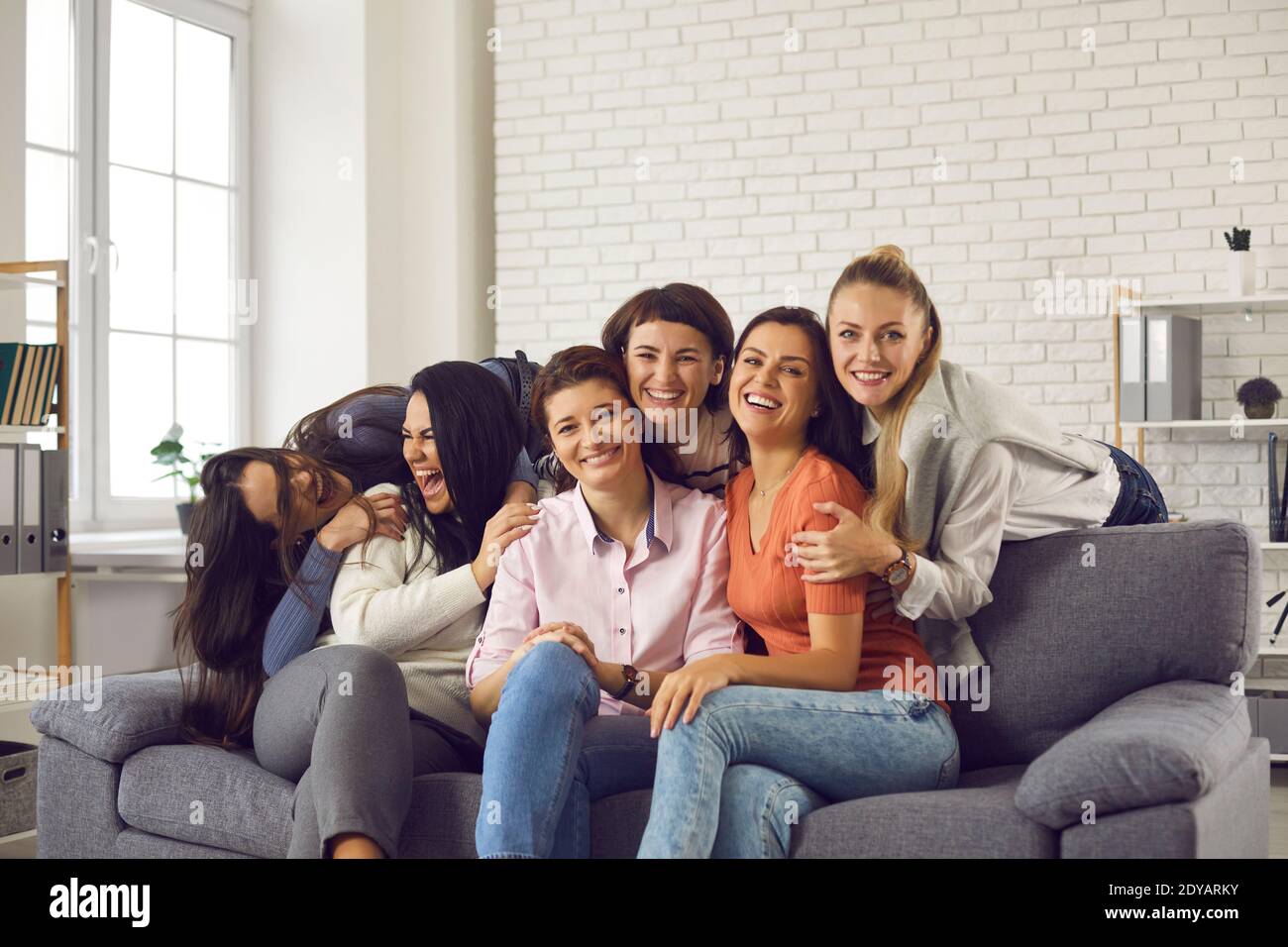 Gruppe glücklicher junger Frauen, die während des Lachens und Narrens herumlaufen Tolles Get-together zu Hause Stockfoto