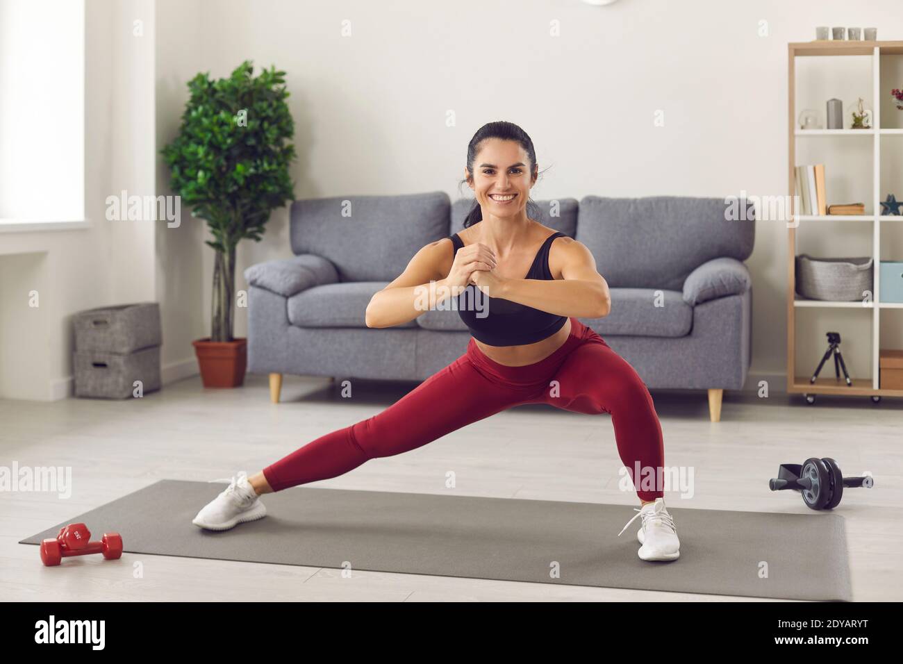 Glücklich hübsche junge Frau Athlet in Sportswear tun Workout mit Kniebeugen für die Beine Stockfoto