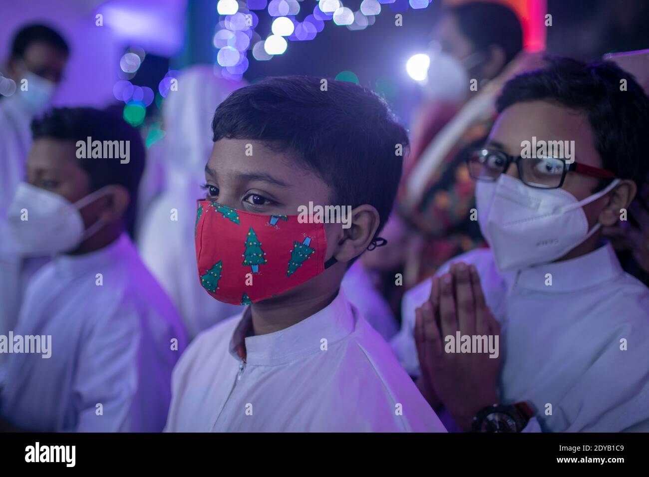 Kinder tragen Masken besuchen Gebete in einer heiligen Rosenkranz katholischen Kirche während Heiligabend.Bangladesch feiert Weihnachten, den Geburtstag von Jesus Christus, Aber aufgrund der Covid-19-Pandemie in diesem Jahr wird der Tag in begrenztem Umfang gefeiert werden, wobei die Regeln für die Gesundheit eingehalten werden, einschließlich der Aufrechterhaltung der sozialen Distanzierung und das Tragen von Masken überall. Stockfoto