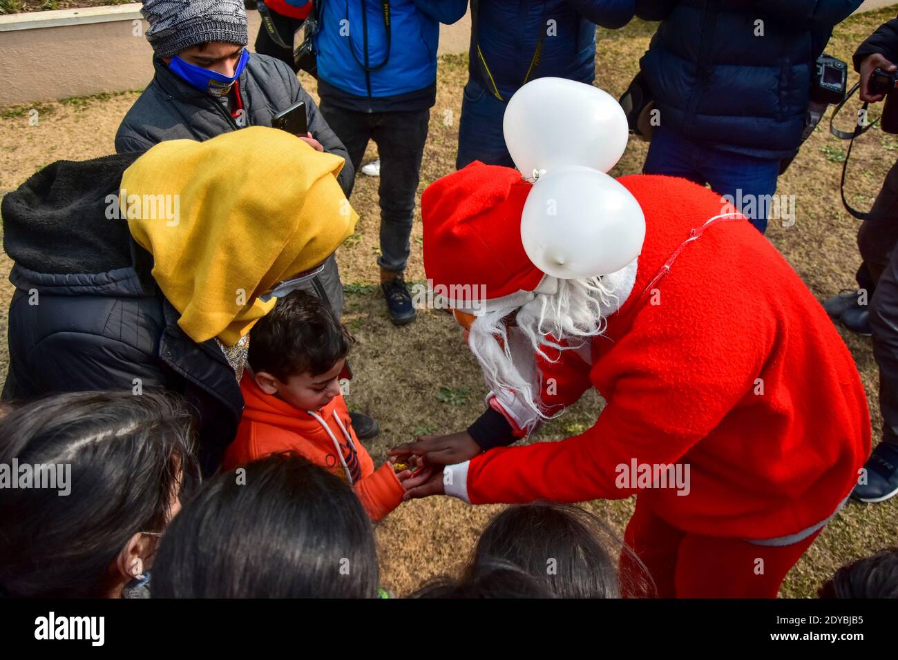 Srinagar, JAMMU & KASHMIR, Indien. Dezember 2020. Ein Mann in einem Weihnachtsmann-Kostüm verteilt Süßigkeiten unter Kindern außerhalb der katholischen Kirche der Heiligen Familie während der Weihnachtszeit. Kredit: Saqib Majeed/SOPA Images/ZUMA Wire/Alamy Live Nachrichten Stockfoto