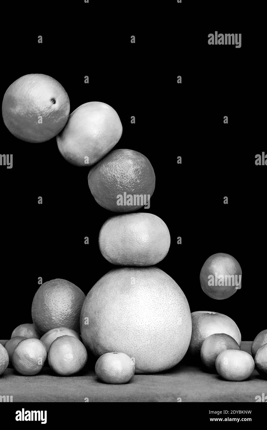 Monochromer fallender Turm aus Zitrusfrüchten, Orangen, Pomelo, Limetten, Mandarinen und Grapefruits isoliert auf schwarzem Hintergrund Stockfoto