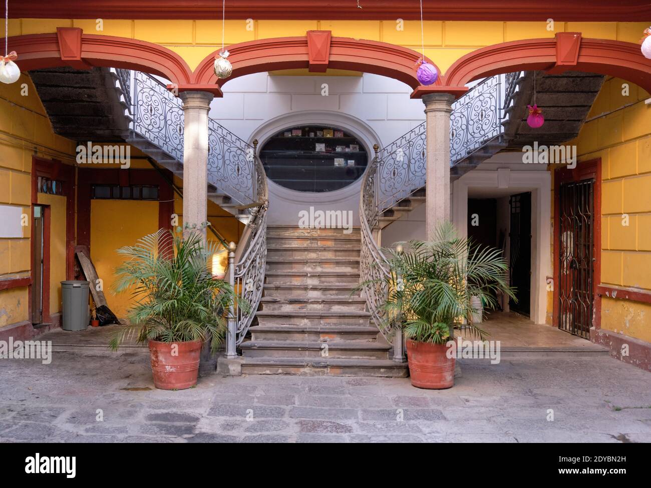 Im Inneren des mexikanischen Innenhofs mit Treppen, die sich auf beiden Seiten nach oben führen Gelb gestrichene Bögen Stockfoto