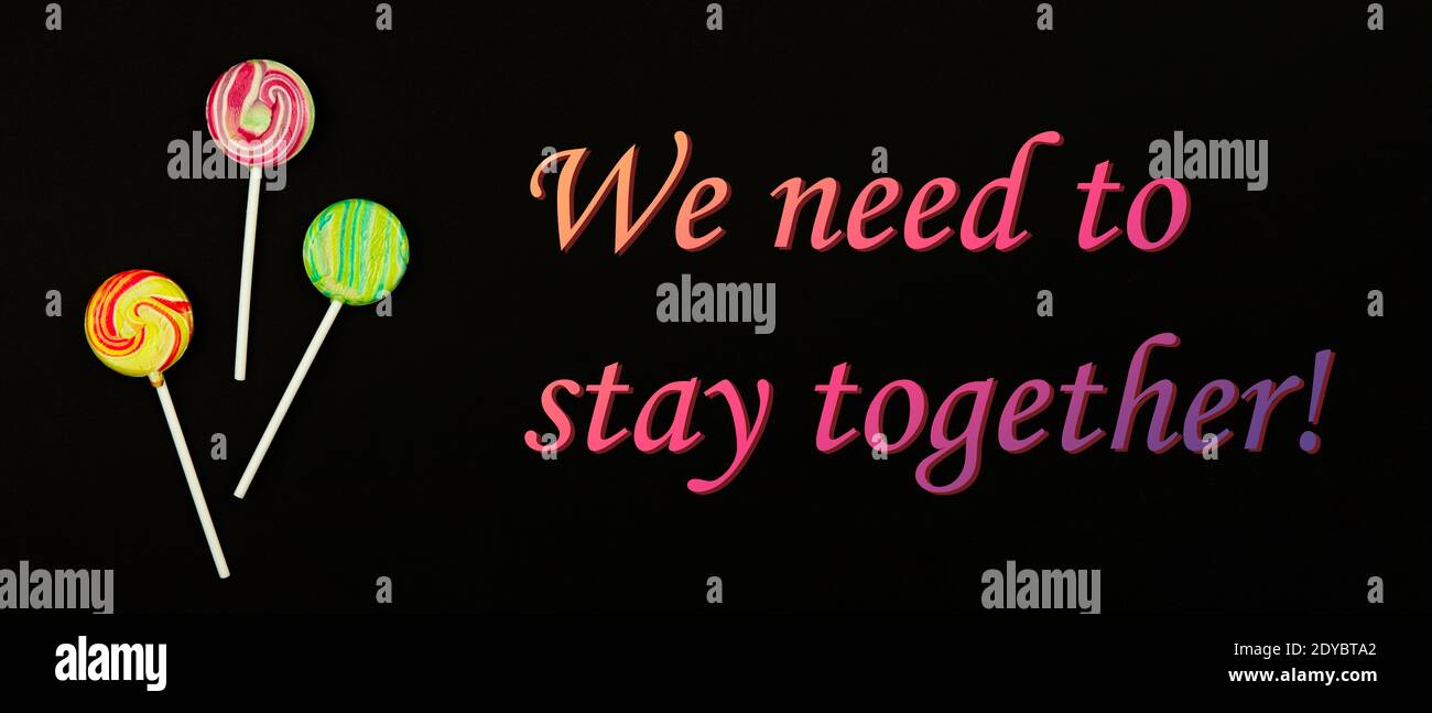 Wir müssen zusammen bleiben, Motivations-Slogan in einer schwierigen Lebensphase, Pandemie, Lutscher auf einem schwarzen Hintergrundfoto Stockfoto
