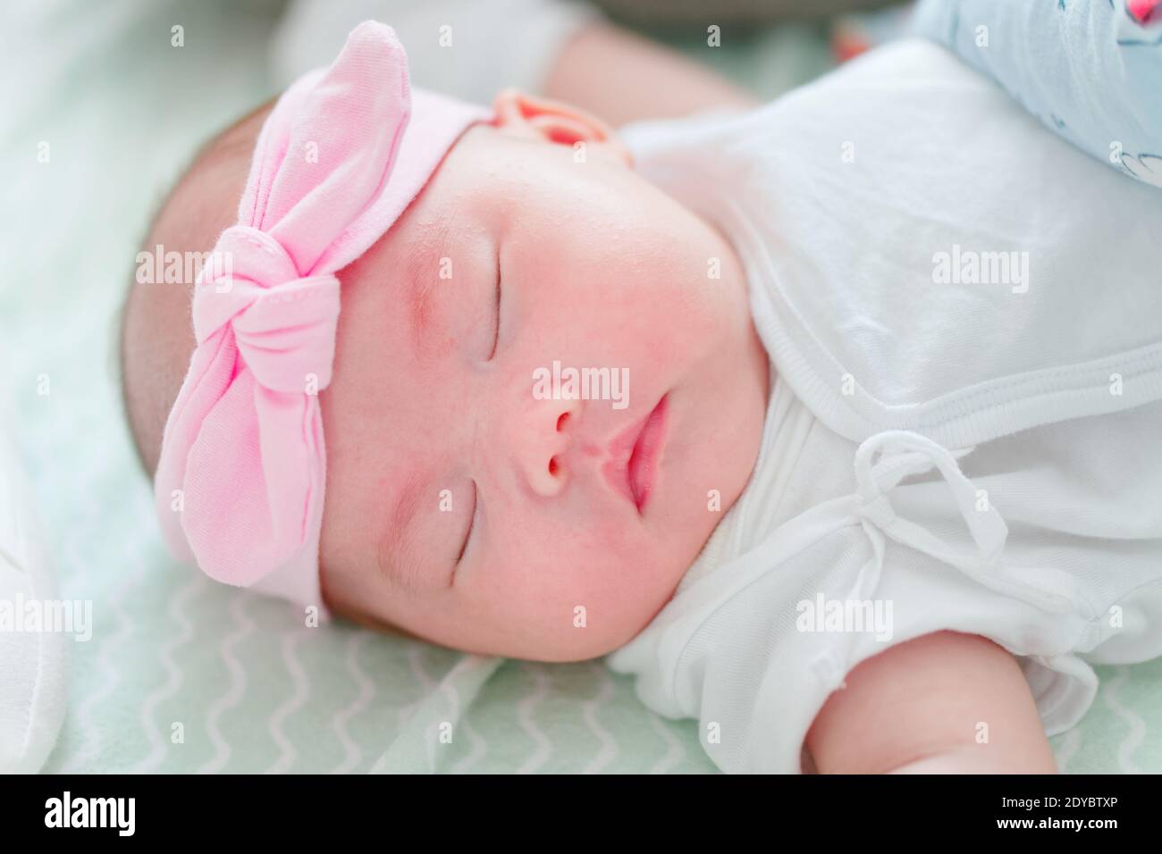 Neugeborenes chinesisches Baby Mädchen nur einen Monat alt schlafen solide  mit rosa Band auf dem Kopf Stockfotografie - Alamy