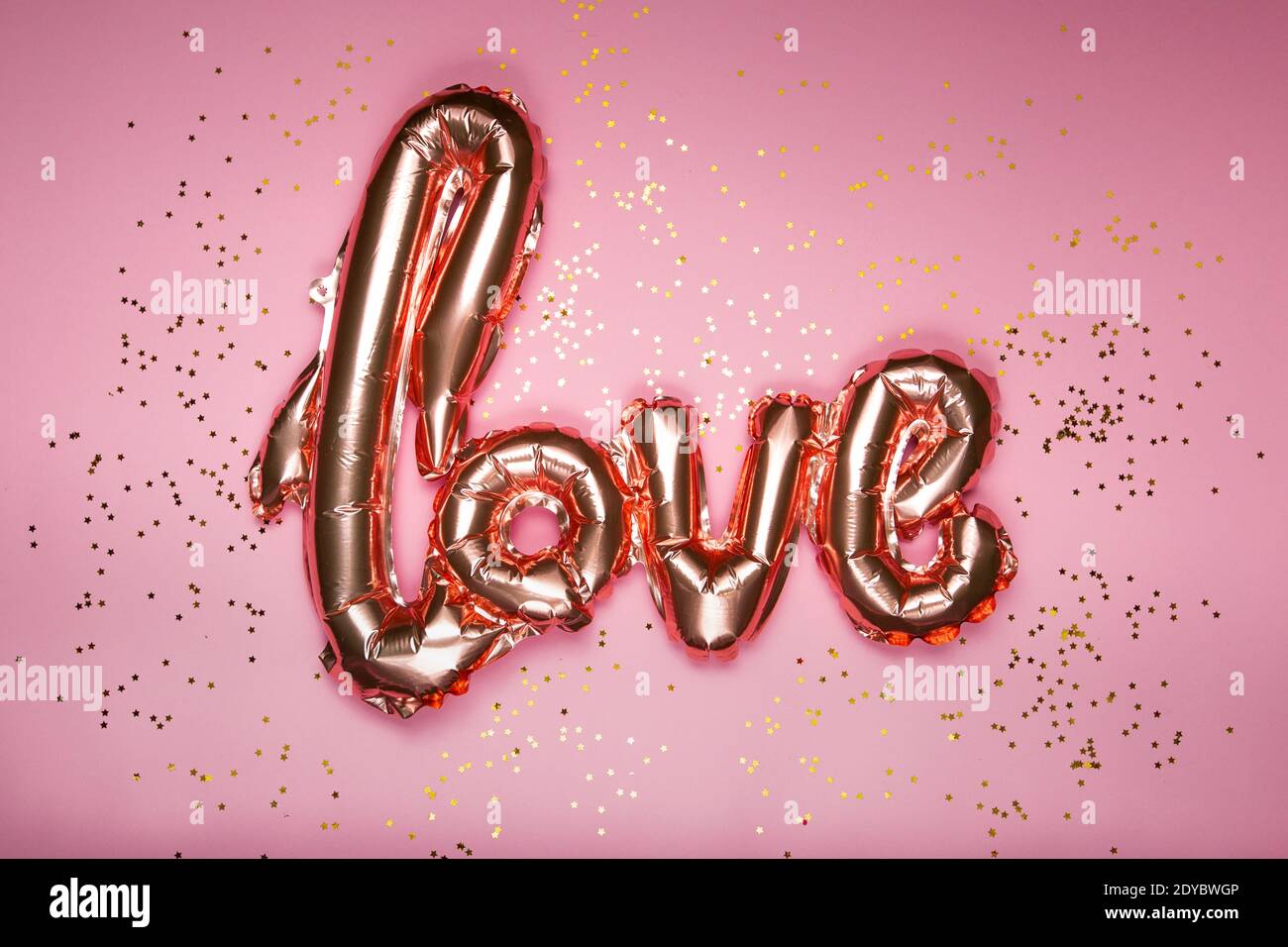 goldenes Wort Liebe auf rosa Hintergrund, Valentinstag Stockfoto