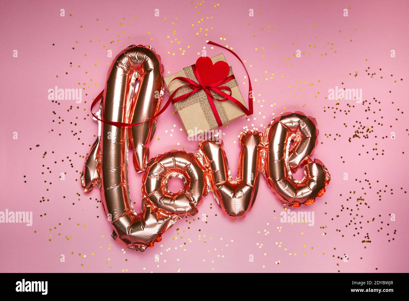 goldene Wort Liebe mit Geschenkbox auf rosa Hintergrund Stockfoto