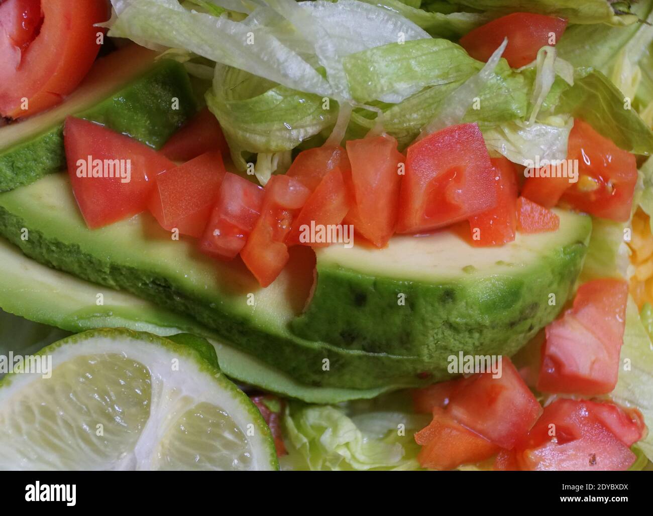 Nahaufnahme der in Scheiben geschnittenen Avocado mit Tomate, Salat und Limette Stockfoto