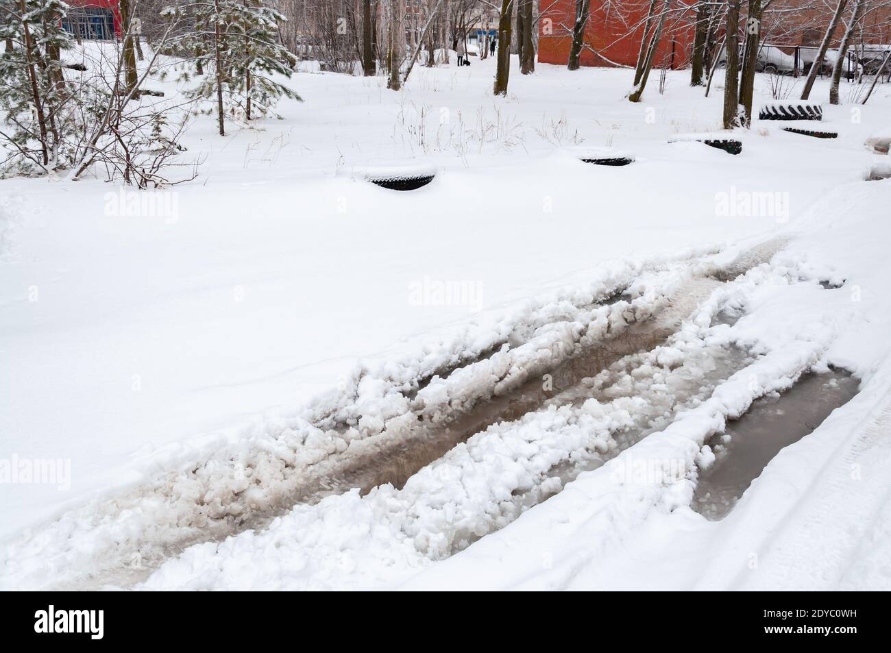 Geschmolzener Schnee auf einer Asphaltfläche mit tiefem Wasser und Schnee an den Rändern. Pfützen auf einer verschneiten Straße im Frühjahr. Stockfoto