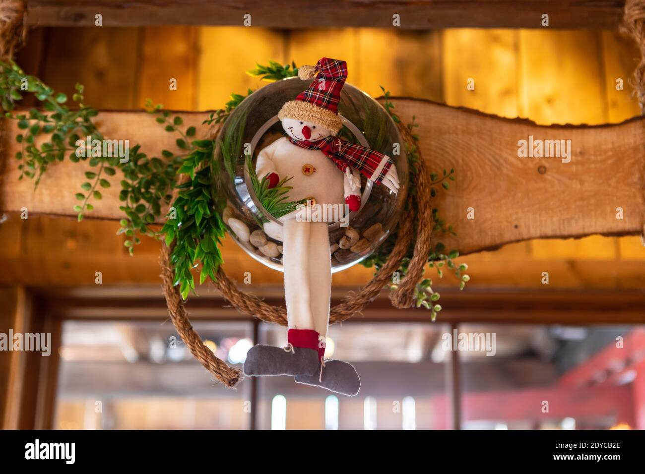 Selektive Fokus von lächelnd gefüllte Schneemann Spielzeug mit Kranz und Blätter auf Holzstück als Dekoration für weihnachten und verwendet Neujahr im Restaurant Stockfoto