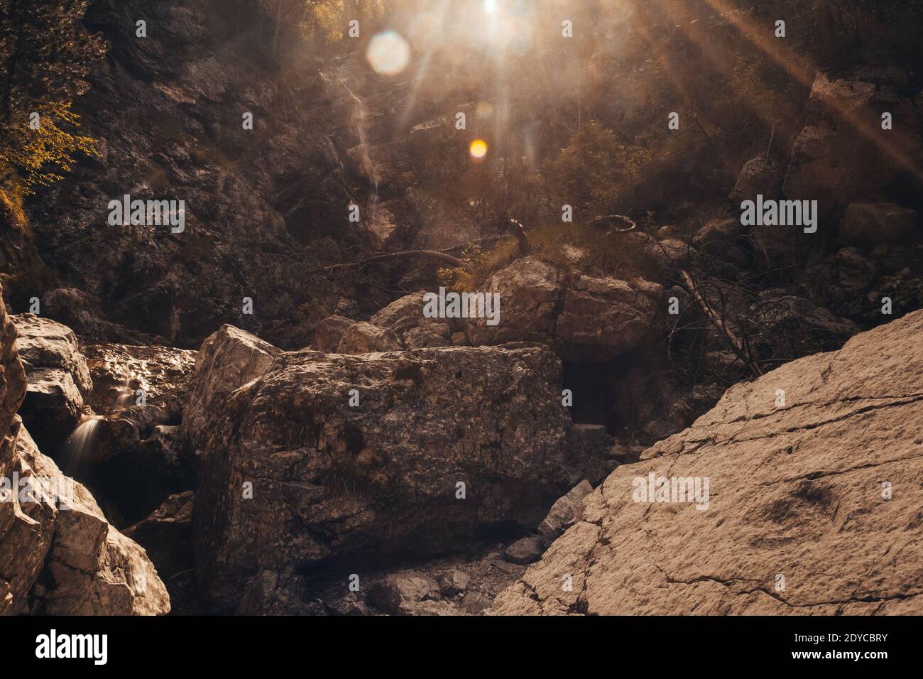 Felsige Schlucht mit großen Felsbrocken gefüllt. Auf der rechten Seite ist ein Dinosaurier Fußabdruck zu sehen, Monte Resettum, Friaul, Italien. Gegen das Licht schießen Stockfoto