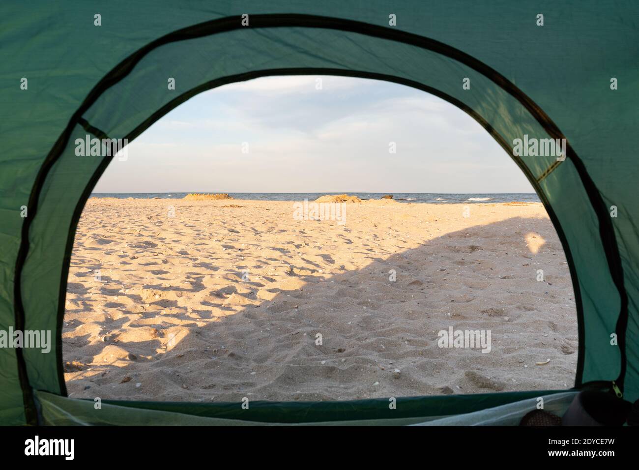 Blick von der Innenseite des Zeltes auf Meer und Sandstrand. Camping am Meer. Stockfoto