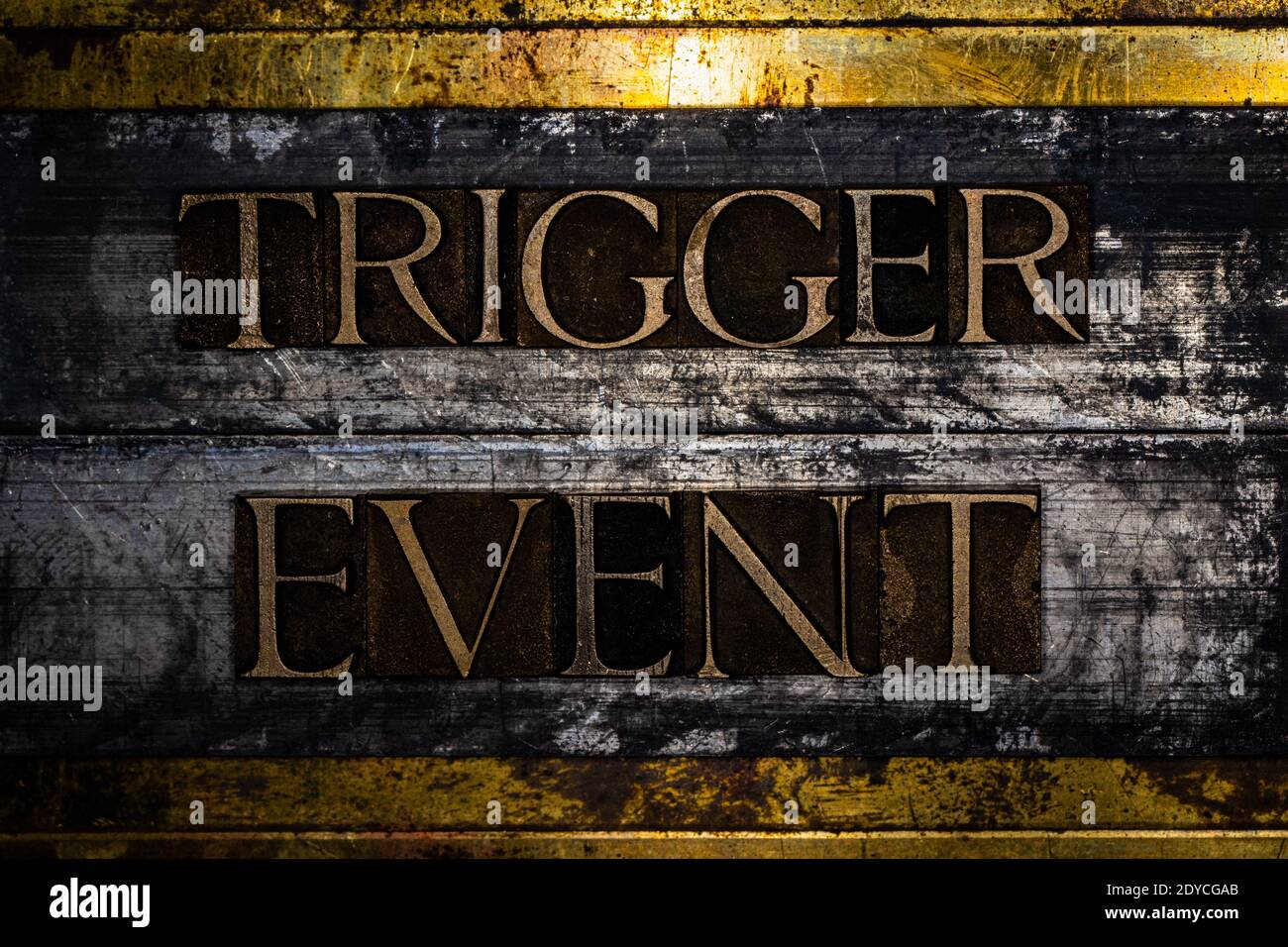 Trigger Event Text auf grunge texturiertem Kupfer und Gold Hintergrund Stockfoto