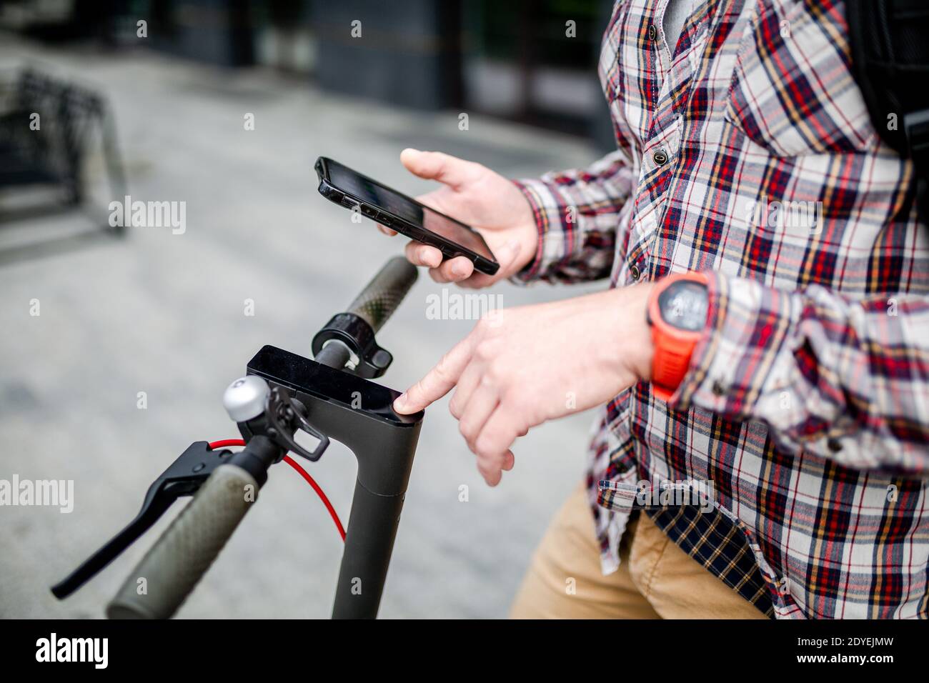 Hände männlich hält Smartphone entsperren Elektroroller Verleih, close-up. Moderne umweltfreundliche alternative Verkehrsmittel in der Stadt, persönliche Mobilität in Stockfoto