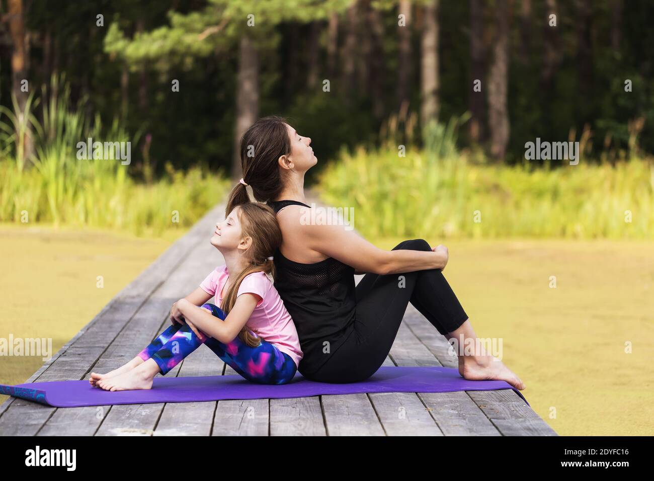 Mutter und kleine Tochter ruhen sich nach den morgendlichen Übungen an der frischen Luft aus. Stockfoto