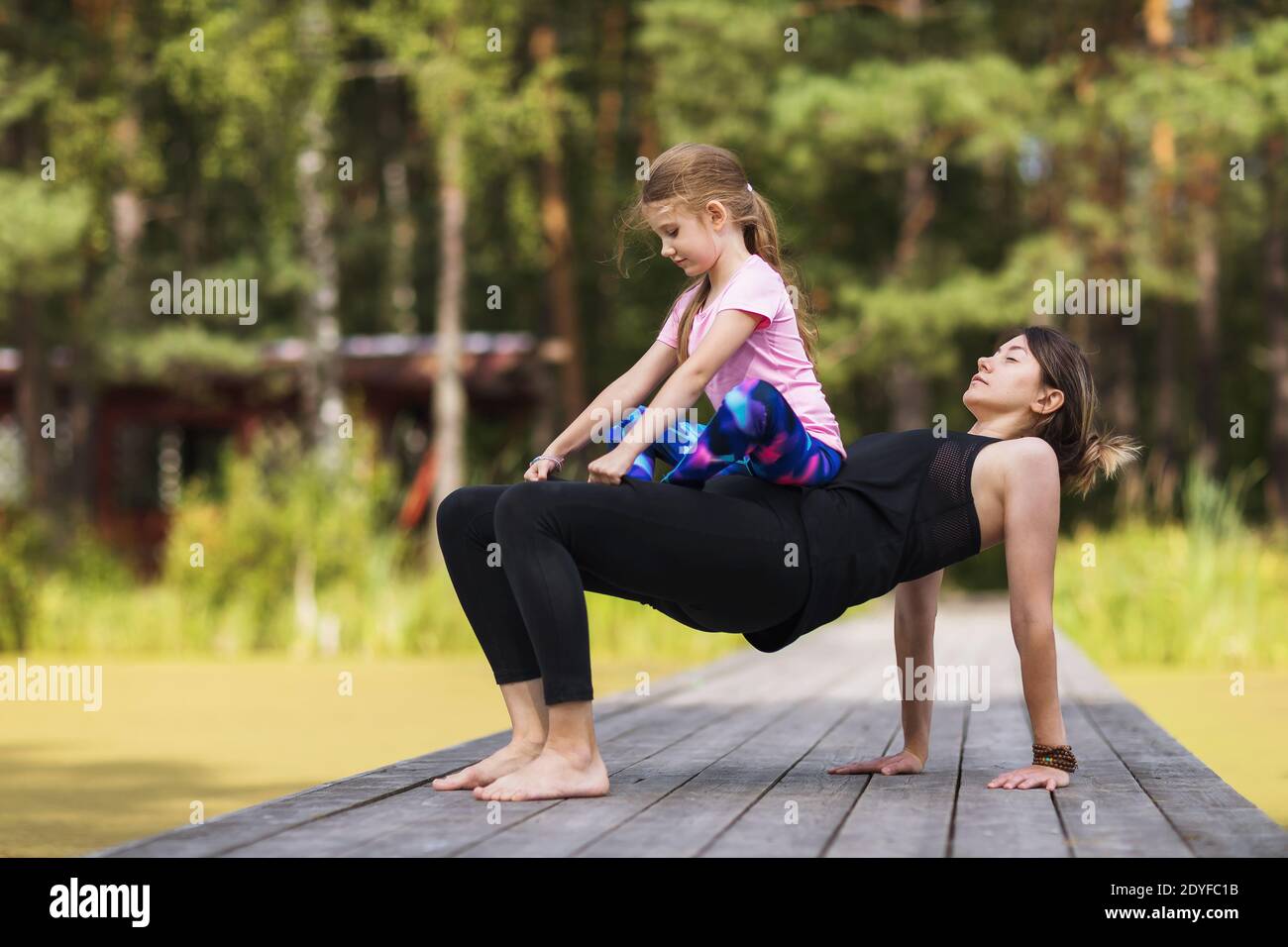 Mama und kleine Tochter trainieren an einem sonnigen Sommermorgen in der Natur. Stockfoto