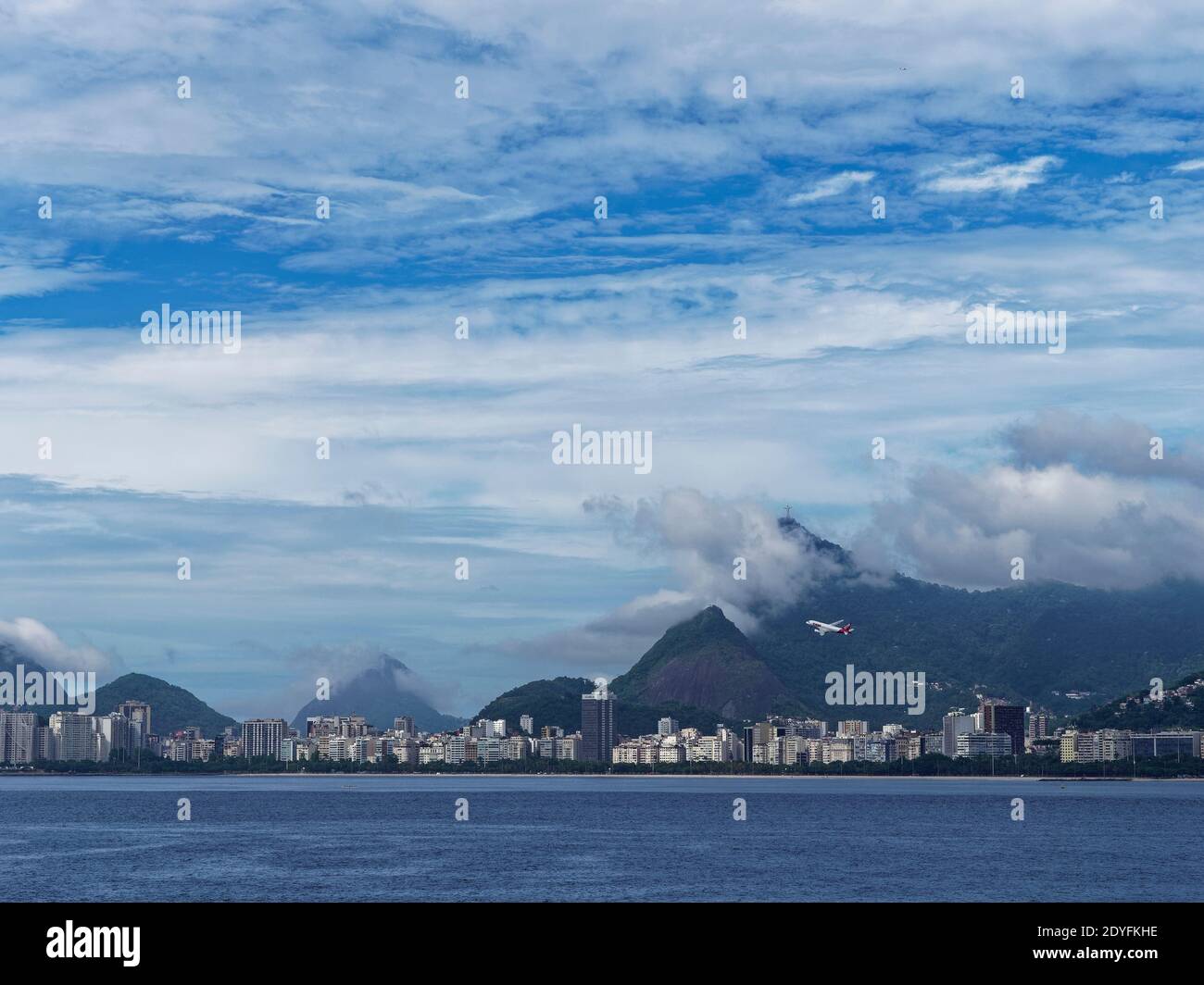 Ein TAM-Flugzeug, das vom Flughafen Santos Dumont vor dem Copacabana-Strand abfliegt, und die Christusstatue in Rio de Janeiro. Stockfoto