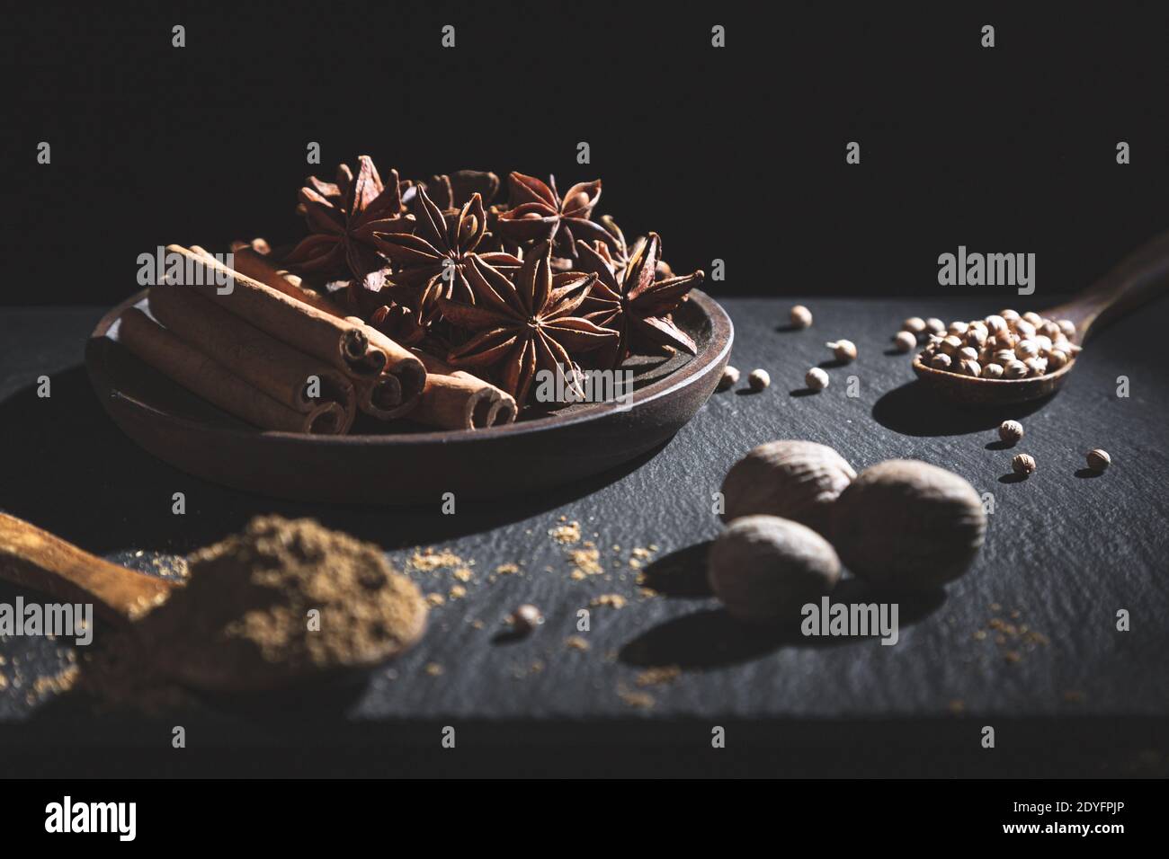 Zimtstange, Sternanis, Muskatnuss, Koriander und gemahlener Kreuzkümmel, auf dunklem Hintergrund mit Kopierraum. Kochen Zutaten und Gewürze Konzept. Stockfoto