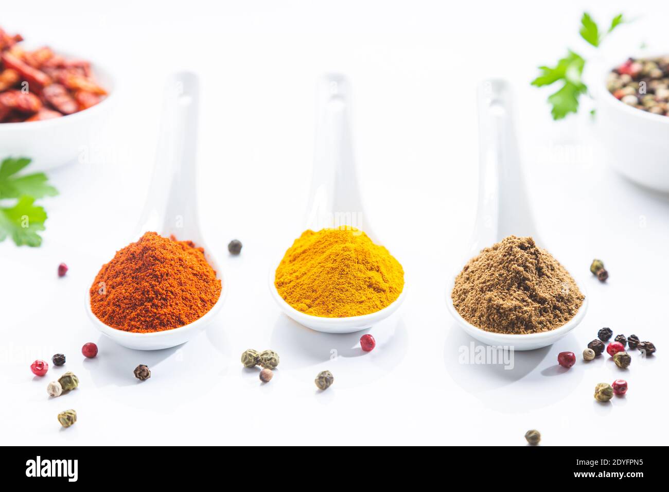 Drei weiße Löffel mit Paprika, Kurkuma und Kreuzkümmel auf weißem Hintergrund. Kochen Zutaten und Gewürze Konzept. Stockfoto