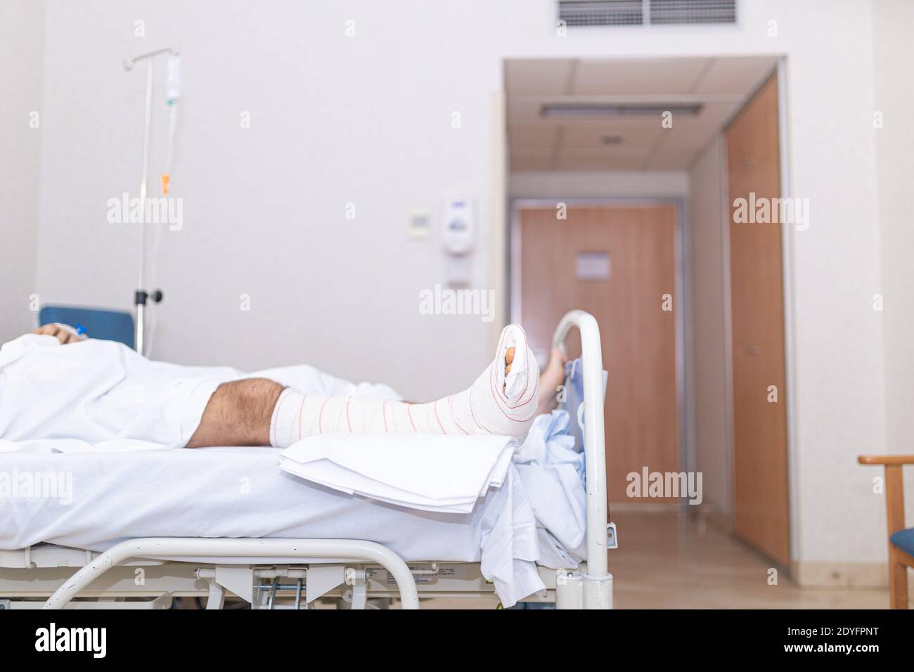 Patient liegt im Krankenhausbett mit gebrochenem Bein. Krankenhausaufenthalt und medizinisches Versorgungskonzept. Stockfoto