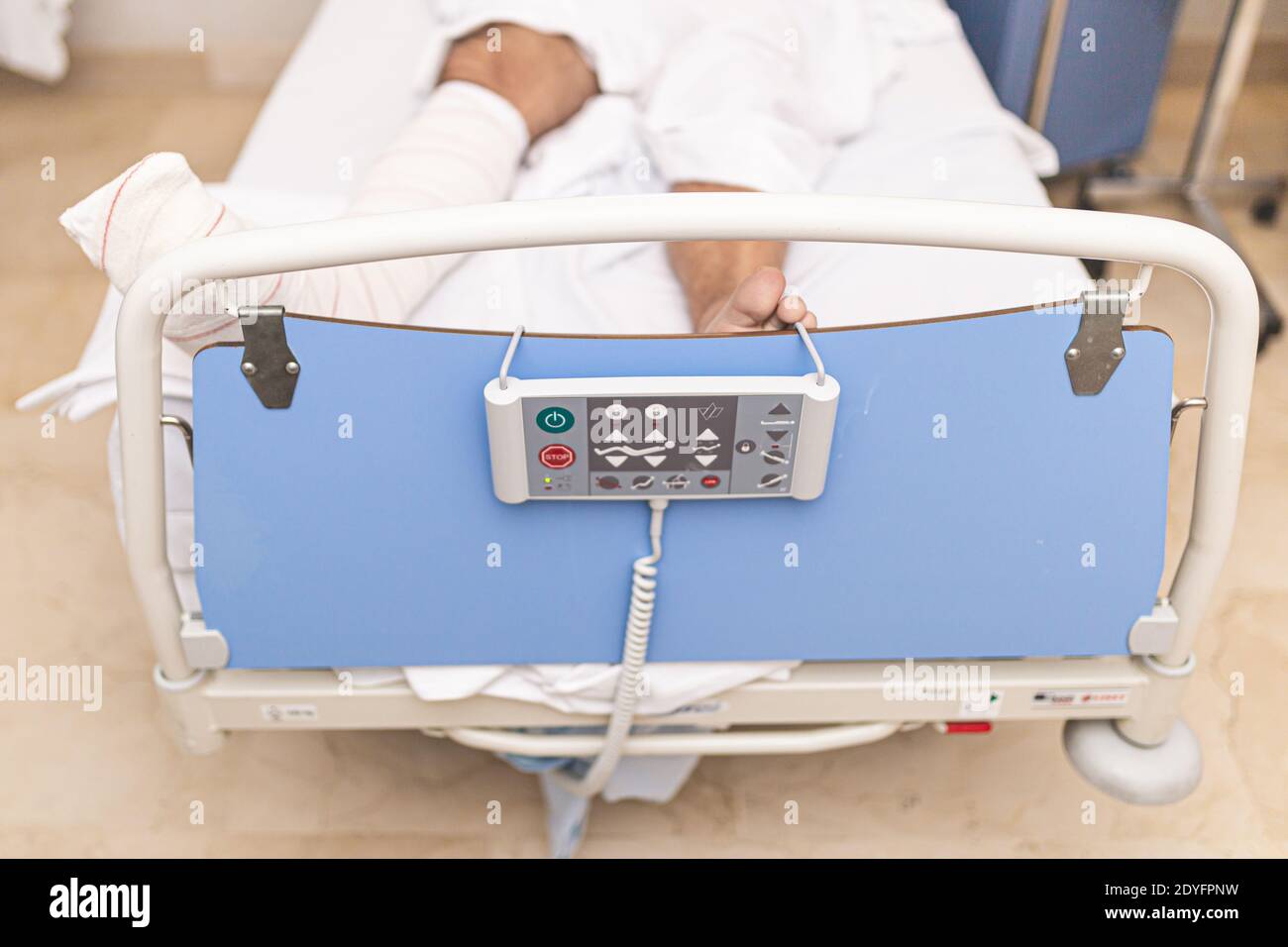 Patient liegt im Krankenhausbett mit gebrochenem Bein. Draufsicht. Krankenhausaufenthalt und medizinisches Versorgungskonzept. Stockfoto