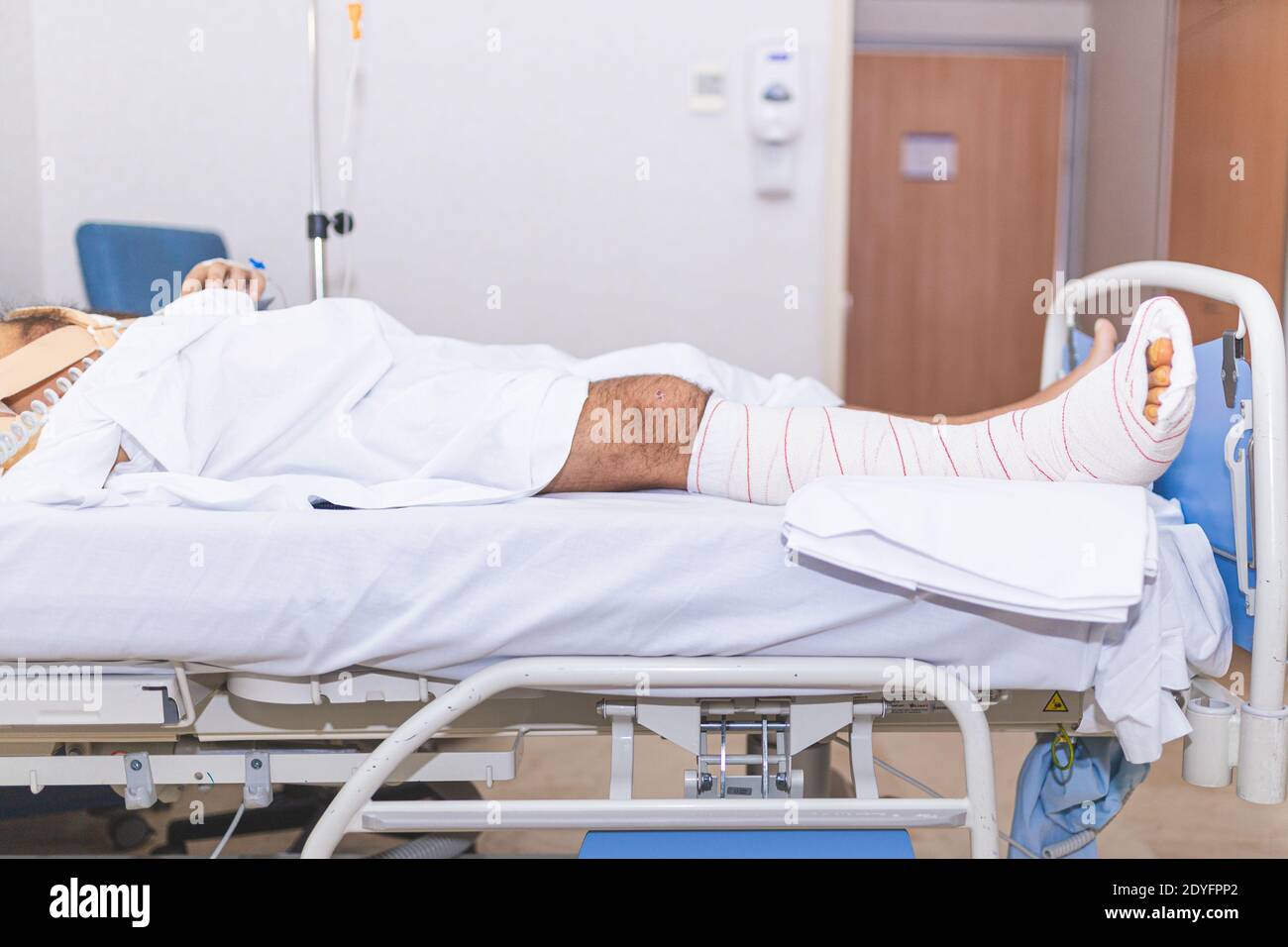 Patient liegt im Krankenhausbett mit gebrochenem Bein. Krankenhausaufenthalt und medizinisches Versorgungskonzept. Stockfoto