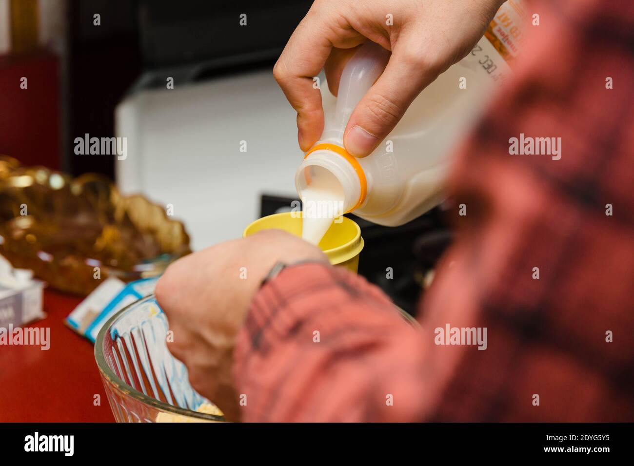 Milch in einen Messbecher gießen, während ein Gericht zubereitet wird Zum Abendessen Stockfoto