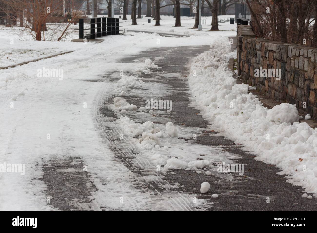 Eine schneebedeckte Straße mit Reifenpanzer im Schnee im Inwood Hill Park, New York Stockfoto