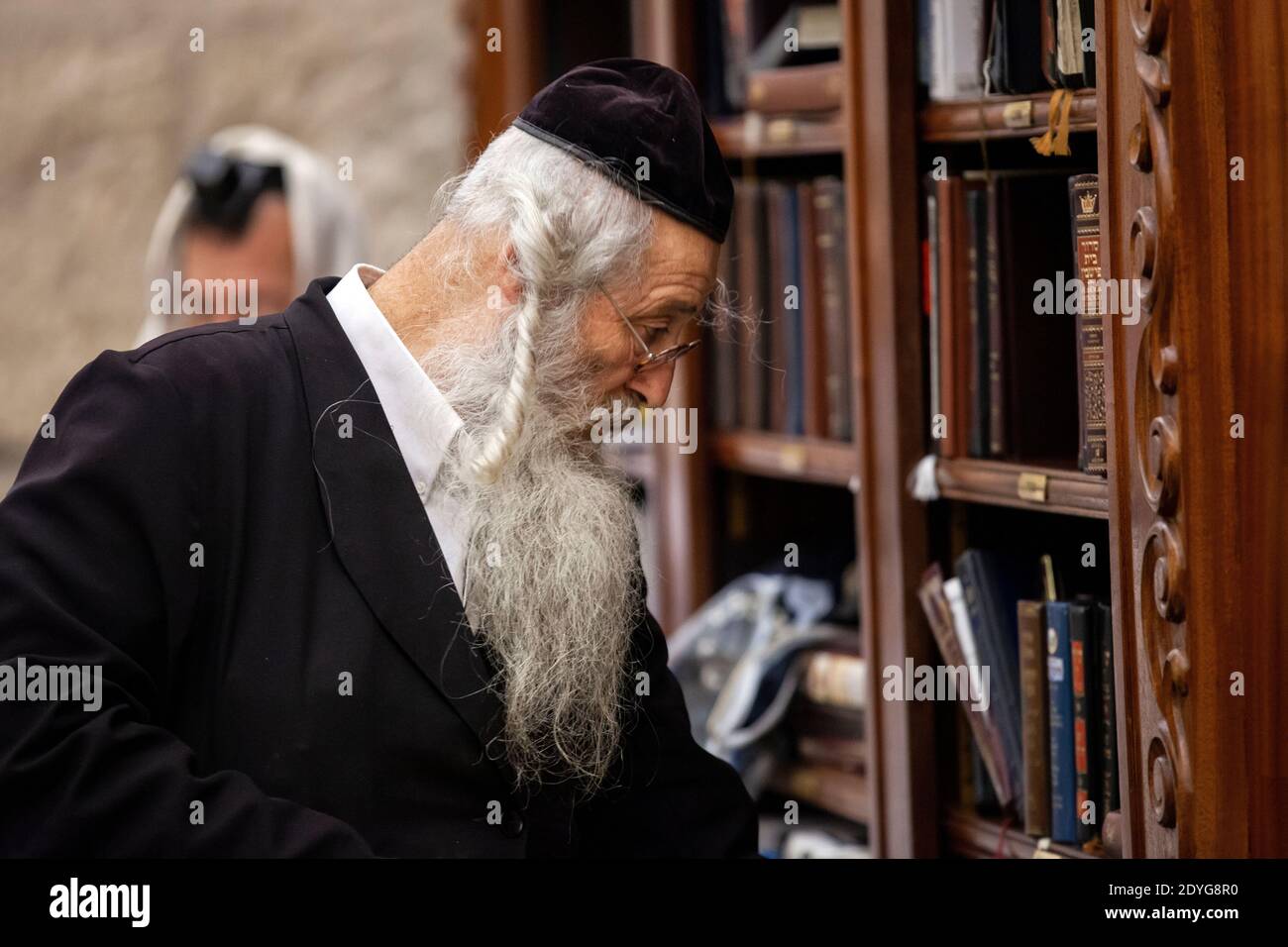 Ein älterer Jude schaut sich religiöse Bücher an der Klagemauer in Jerusalem, Israel, an Stockfoto