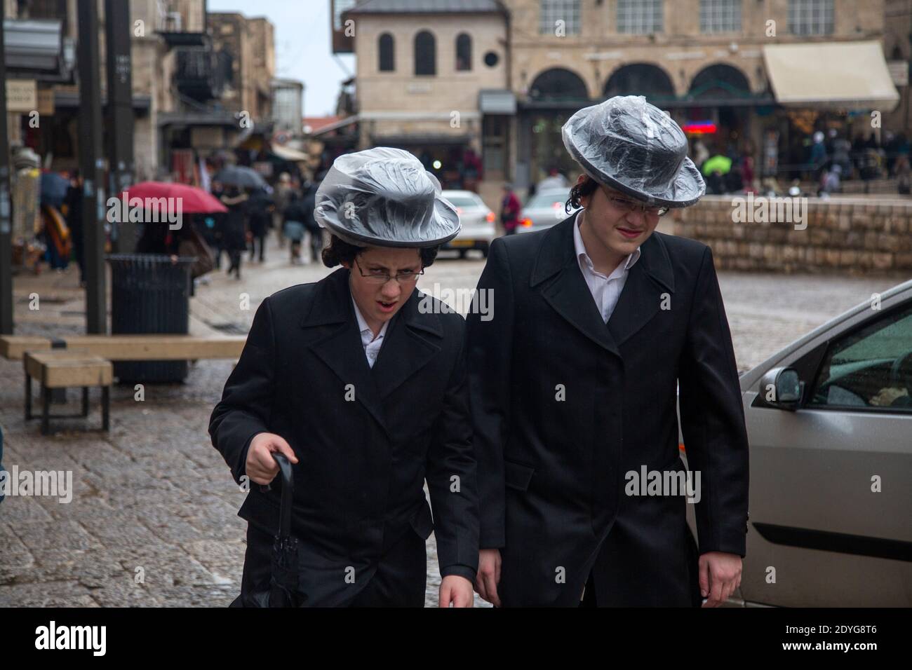 Orthodoxe Juden gehen entlang einer Straße in der Altstadt von Jerusalem Stadt während eines Regens, Israel Stockfoto