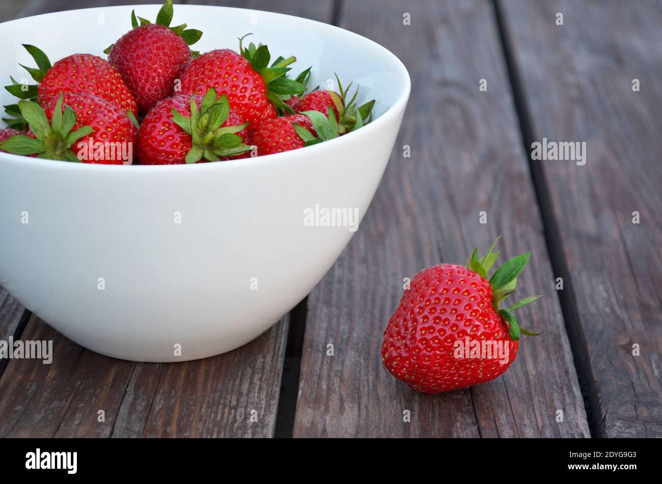 Schüssel mit reifen Erdbeeren auf einem alten Holztisch Nahaufnahme. Gesunde Ernährung Konzept. Stockfoto