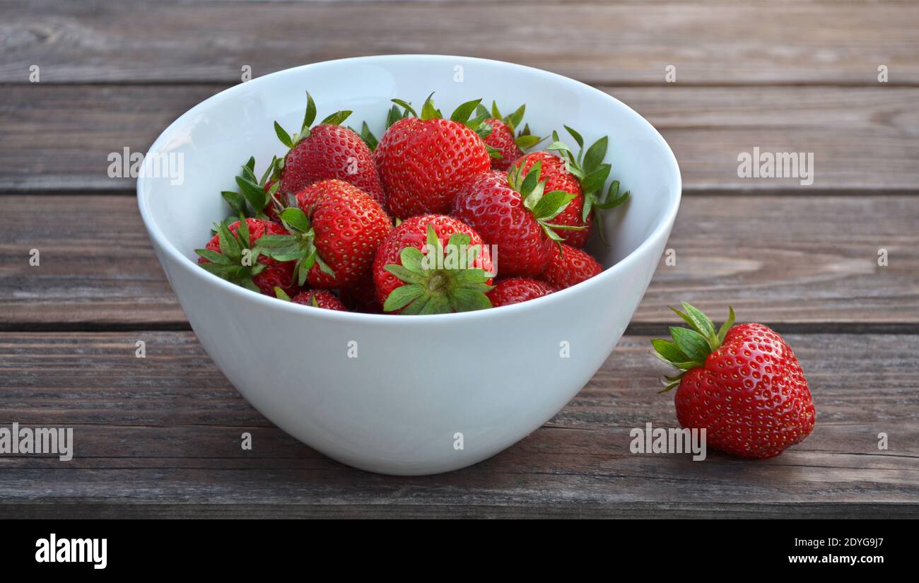 Schüssel mit frisch gepflückten Erdbeeren auf einem alten rustikalen Holztisch aus der Nähe. Gesunde Ernährung Konzept. Stockfoto