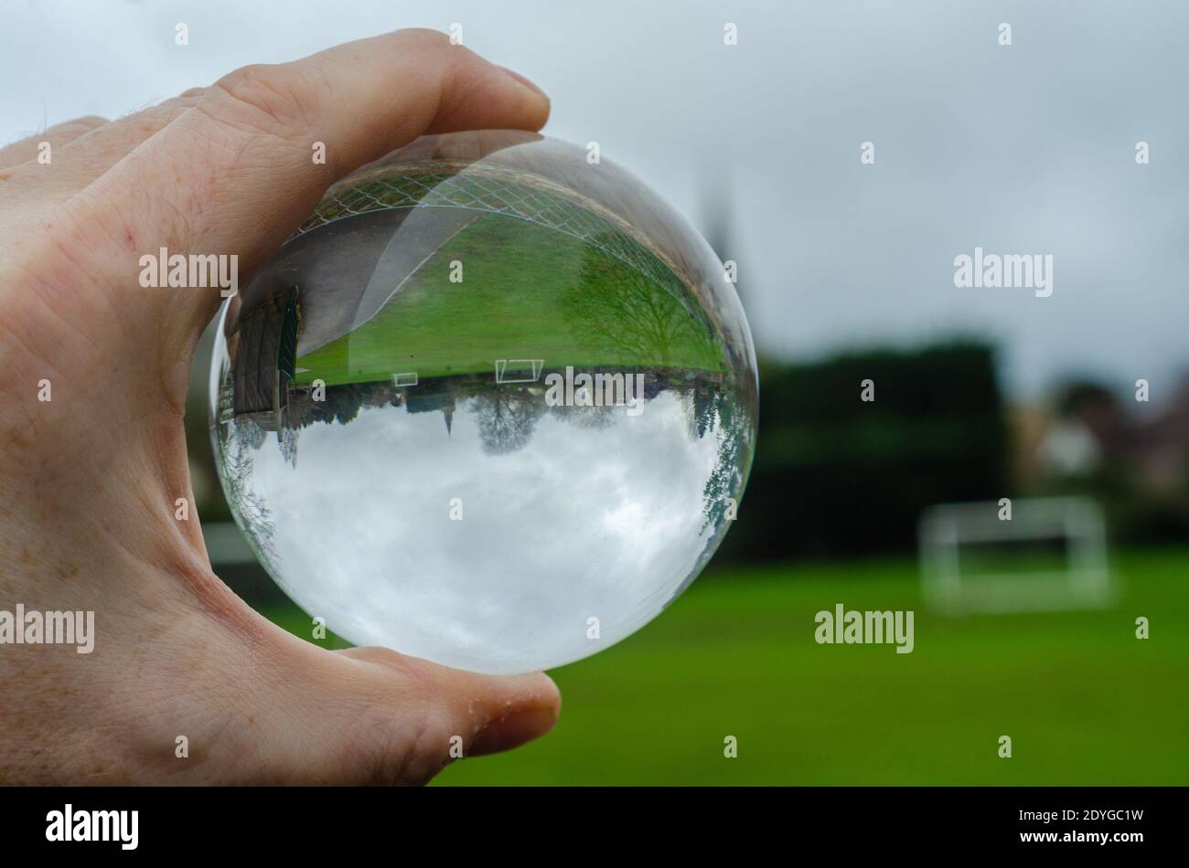 Ein Spielfeld mit Torpfosten ist in einer Glaskugel aufgrund der optischen Wirkung der Brechung kopfüber zu sehen, Stockfoto