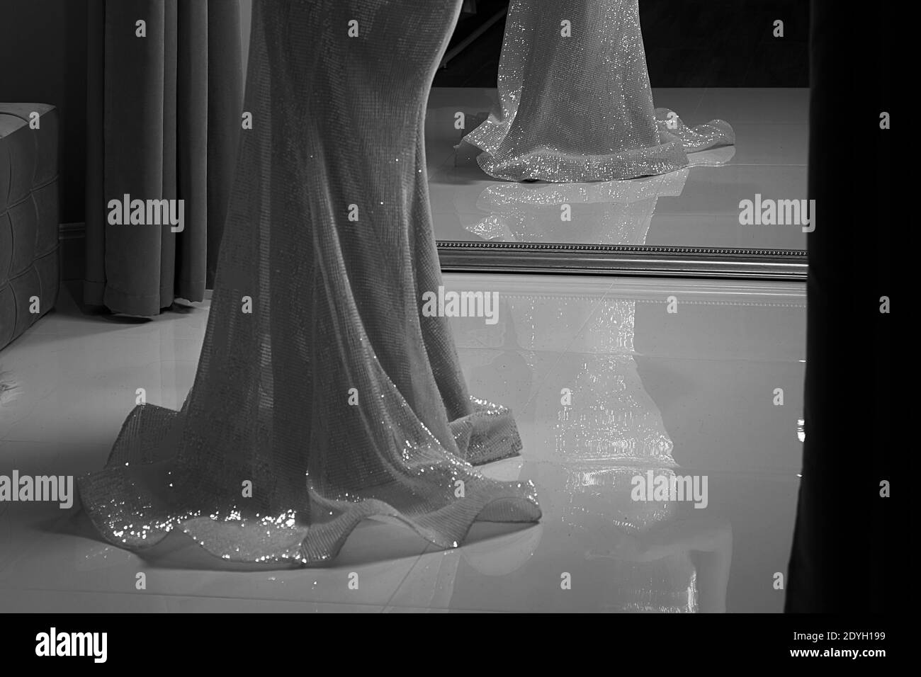 In voller Länge Chiffon Meerjungfrau Kleid oder Ballkleid mit Pailletten verziert. Modell vor Spiegel in Umkleidezimmer. Klassischer Schwarz-Weiß-Stil. Stockfoto