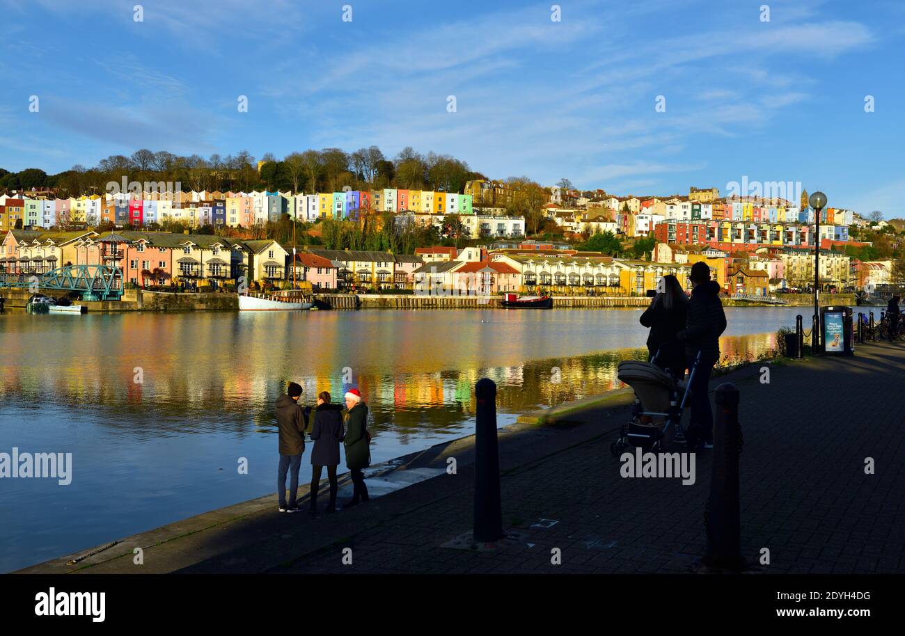 Weihnachtstag Spaziergang, Menschen auf Spike Island Seite von Bristol schwimmenden Hafen mit Blick auf bunte Reihenhäuser in Cliftonwood Hügel silhouetted Stockfoto
