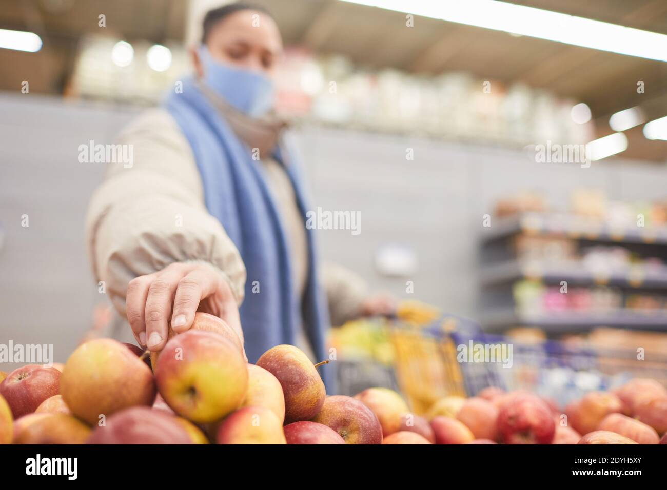 Junge Frau in Maske Auswahl frische Äpfel beim Einkaufen Im Supermarkt Stockfoto