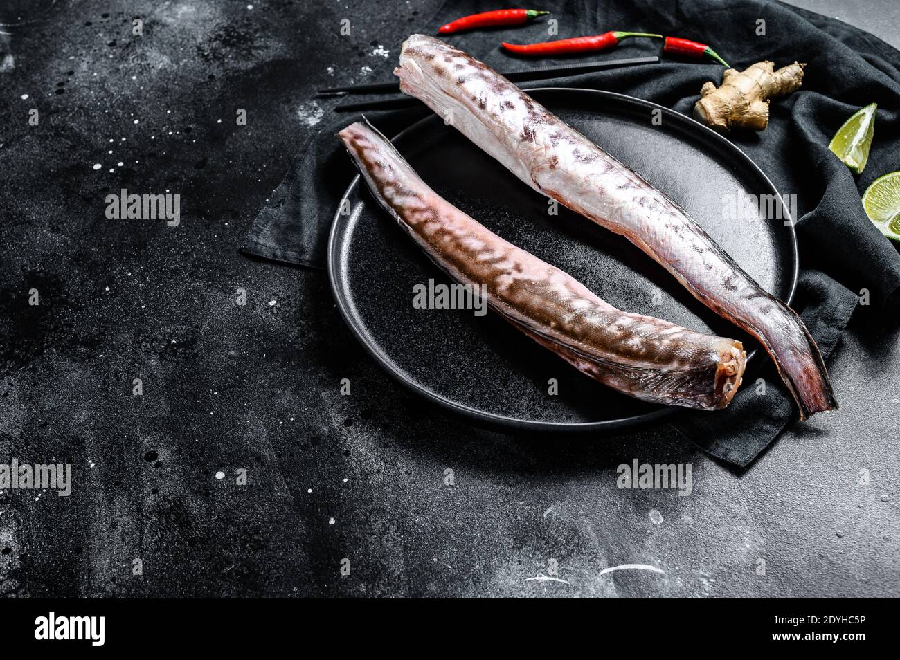 Roher Königsklip, Congrio-Fisch. Schwarzer Hintergrund. Draufsicht. Speicherplatz kopieren Stockfoto