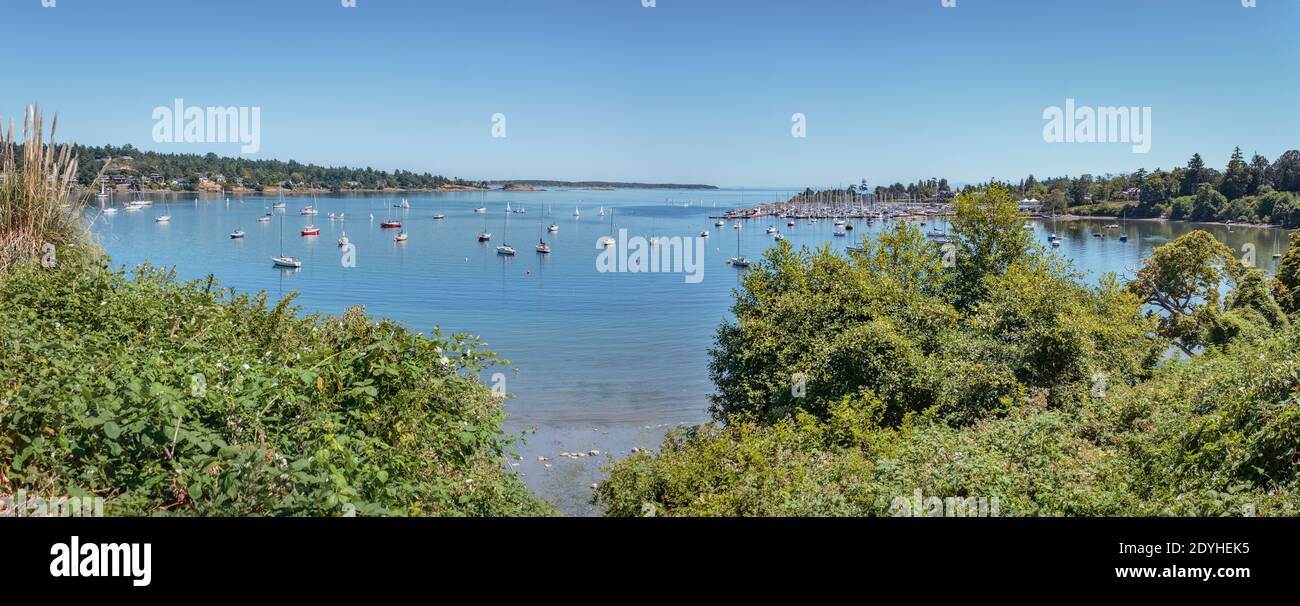 Hunderte von Booten sind Teil einer Panorama-Sommer-Ansicht von Cadboro Bay, mit einem Yachtclub auf der rechten Seite, Ten Mile PT. Auf der linken Seite und Haro Strait in der Ferne. Stockfoto