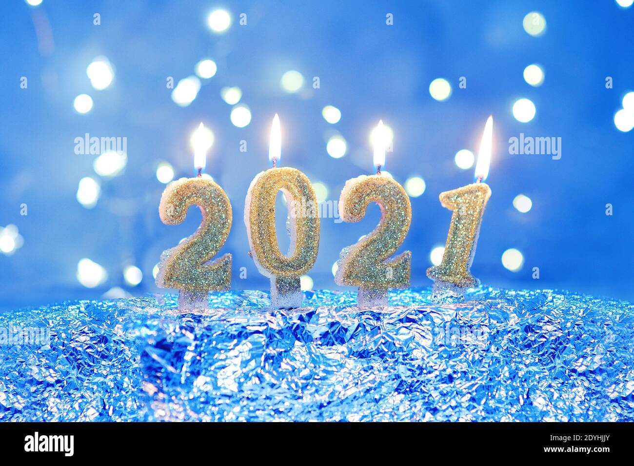 Urlaub Hintergrund Frohes neues Jahr 2021. Zahlen des Jahres 2021 von goldenen brennenden Kerzen auf Bokeh festlich funkelnden Hintergrund. Feiern Neujahr Stockfoto