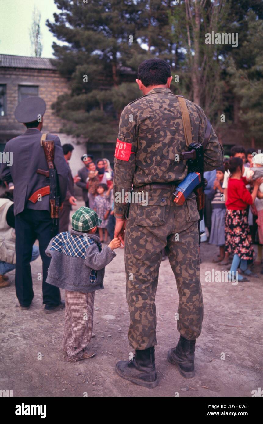 Datei Foto aufgenommen 10/04/1993: Bewaffneter aserbaidschanischer Soldat mit Kind und aserbaidschanischen Flüchtlingen, Binnenvertriebenen oder IDP, aus Fizuli, die in einer Schule in Akhmedbeili am Araz-Fluss im Südosten Aserbaidschans in der Nähe der Grenze zu Aserbaidschan Iran leben. Stockfoto