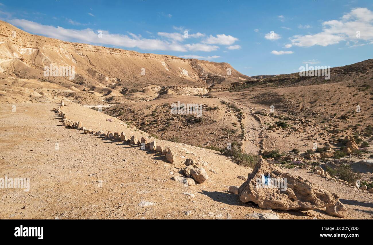 Der Wegleiter zur ein-Akev-Feder am OFF Parkplatz und Campingplatz im nahal akev Bach Bett im Zin-Tal unter einem teilweise bewölkten Himmel Stockfoto