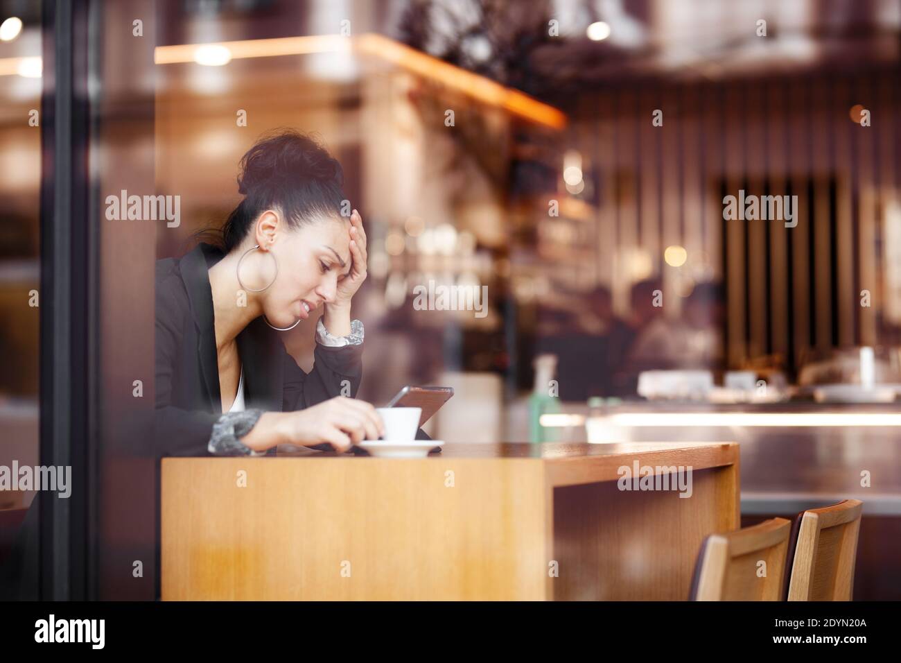 Besorgt Geschäftsfrau in einem Café, Kaffee und Blick auf Tablet. Stockfoto