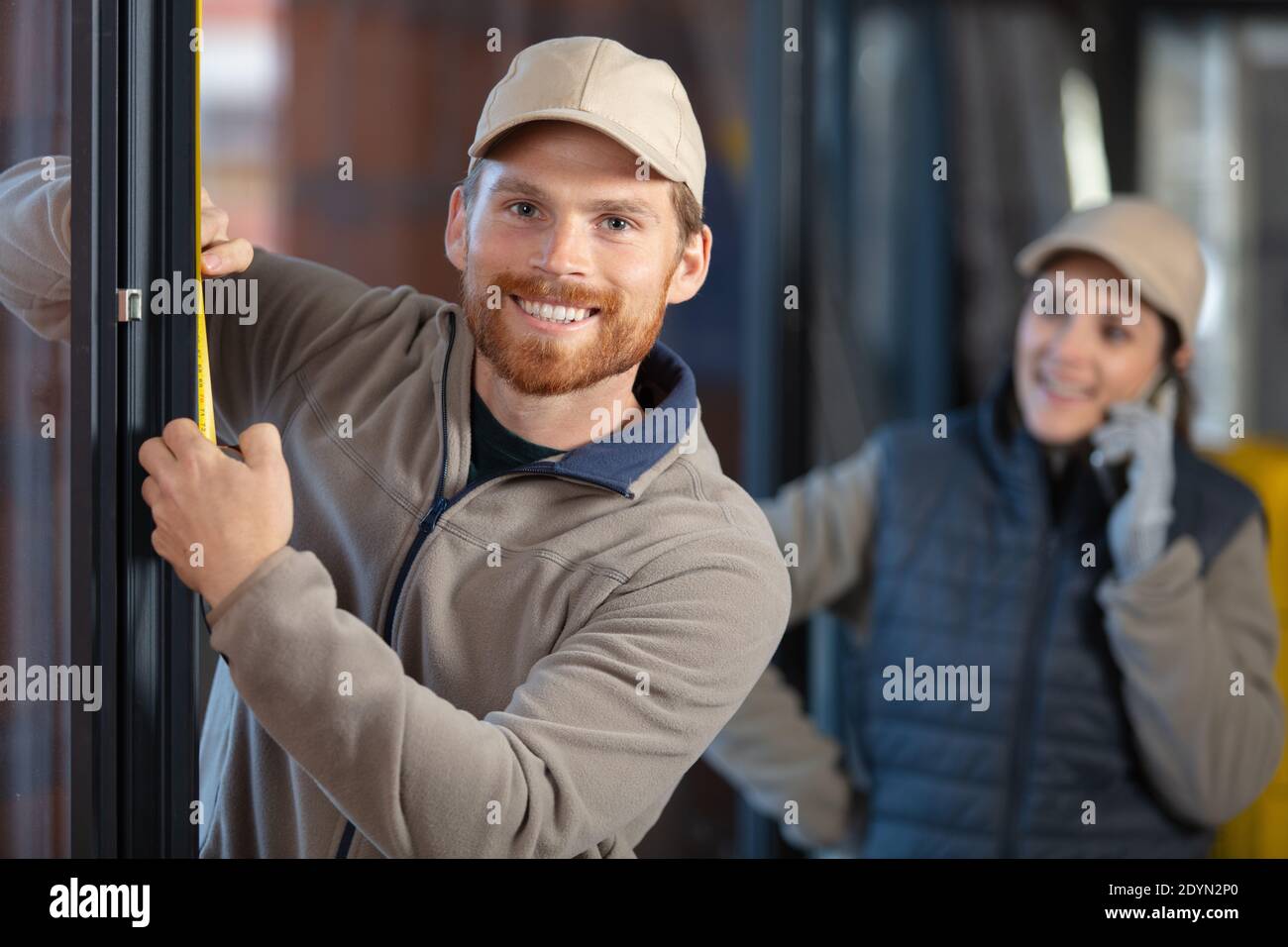 Glücklicher junger Bauarbeiter, der Fenster im Haus installiert Stockfoto