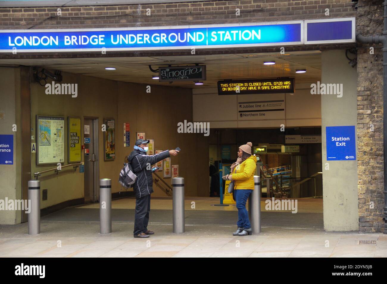 London, Großbritannien. Dezember 2020. Ein Paar sah Stand am Eingang der London Bridge U-Bahn-Station am zweiten Weihnachtsfeiertag.London und Teile von Südostengland waren in Tier 4, während der Weihnachtsferien mit Einschränkungen für die Haushaltsmischung und nicht-wesentliche Geschäfte geschlossen. Die Tier-4-Maßnahmen sind nach dem 30. Dezember zu überprüfen. Kredit: SOPA Images Limited/Alamy Live Nachrichten Stockfoto