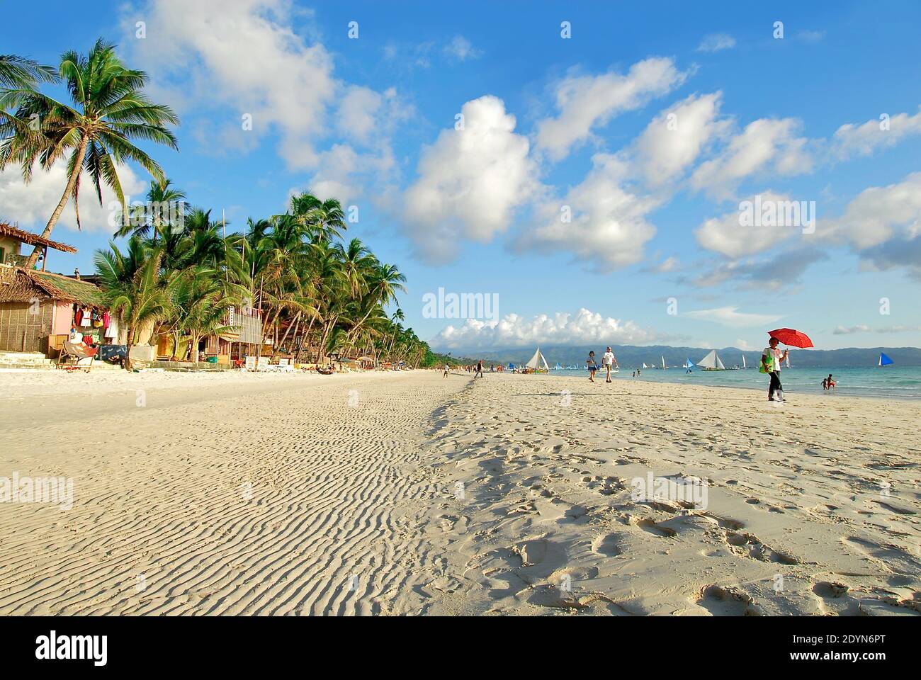Wellen am leeren White Beach auf Boracay Island, Philippinen. Nur wenige Menschen und Segelboote sind vorhanden, mit blauem Himmel, Palmen Hintergrund Stockfoto