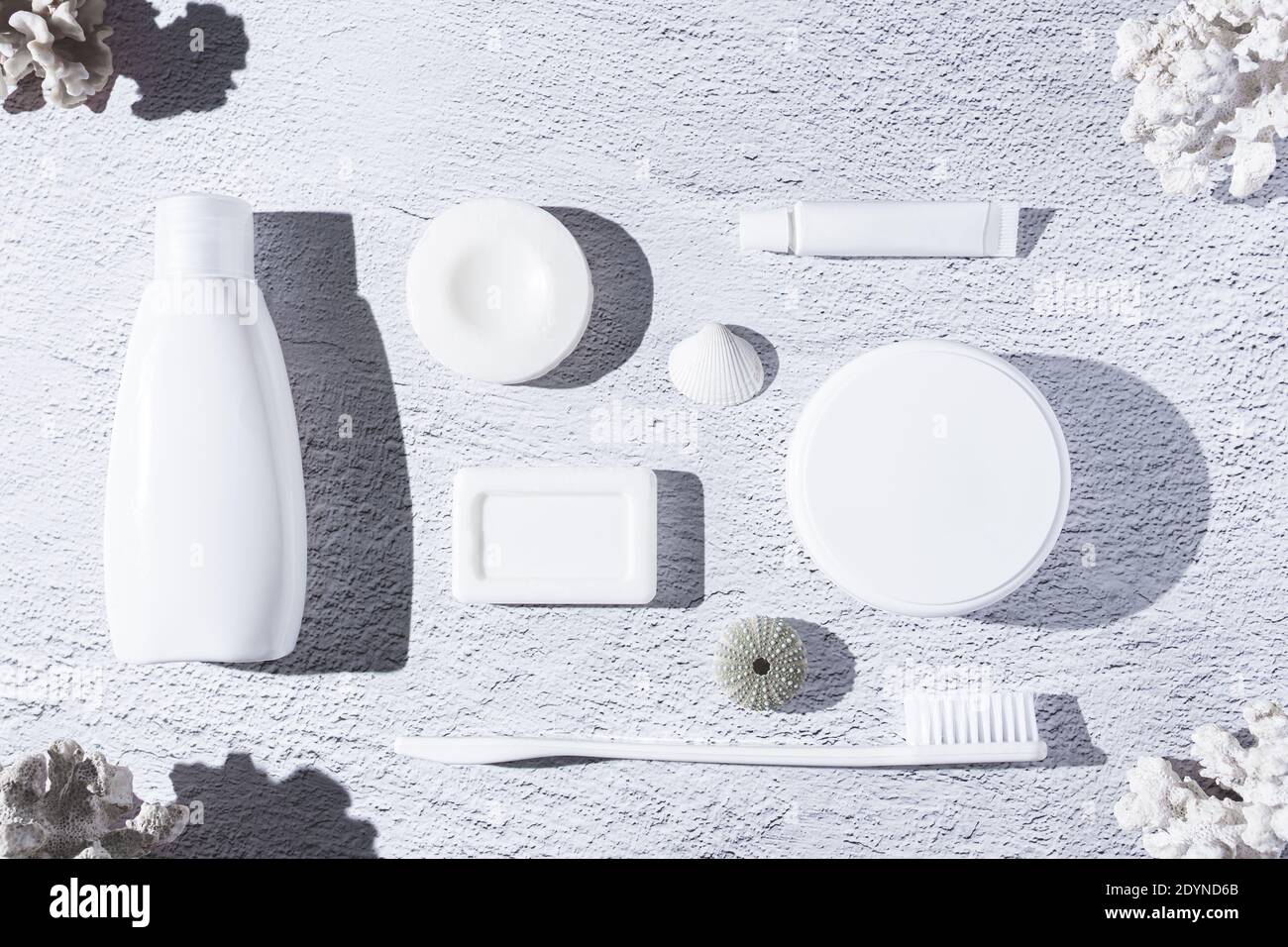 Vielfalt an Körperpflegeprodukten auf weißem Hintergrund mit Korallen und Muscheln. Draufsicht. Stockfoto
